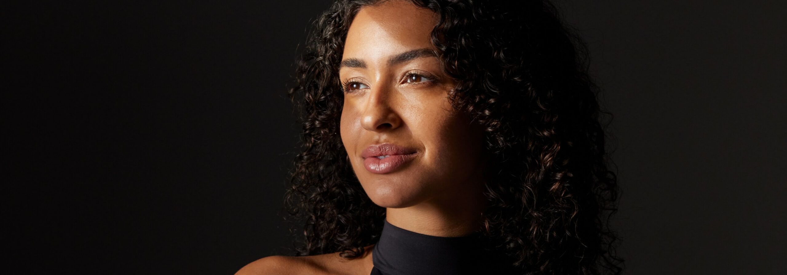 An adult woman looking away from the camera with dramatic lighting.