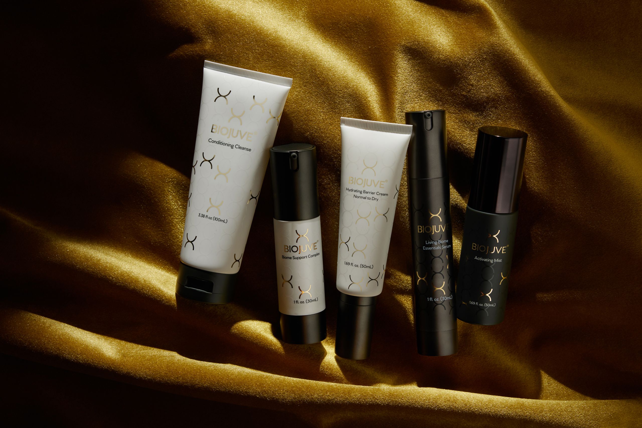 The full BIOJUVE product lineup on gold fabric.